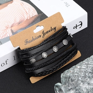 Détail d'un ensemble de bracelets en cuir noir tressé avec rivets étoiles sur carte brune