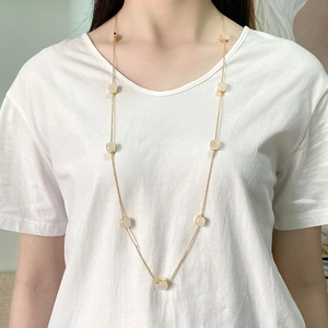 Detail of long gold chain necklace with square milky white crystal pendant on a model