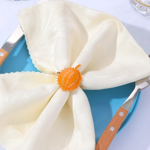 Detail of metal durian fruit napkin ring on cloth napkin with blue ceramic plate
