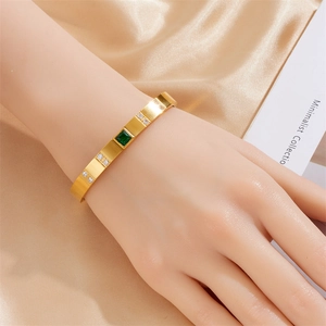 Elegante bracciale in acciaio al titanio dorato con gemma verde quadrata e dettagli