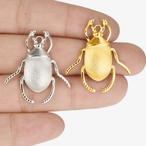 304 stainless steel beetle pendants in gold and silver finish shown for size on a finger