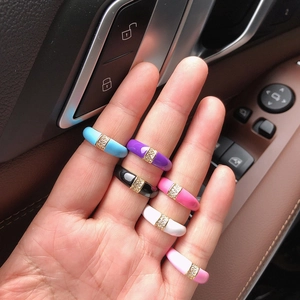 Detailed view of colorful enamel rings with inlaid crystals on female hand in sunlight