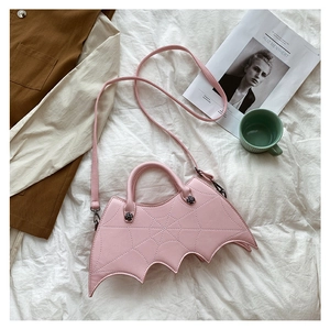 Detailed close-up of pink bat wing PU leather handbag with spiderweb stitching on white sheets