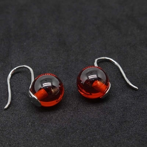 Macro shot of deep red transparent globe earrings with silver hooks on black background