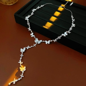 Détail du collier argenté en Y avec papillon en zircon et charmes de fleurs en nacre