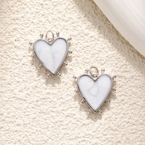 Close-up of heart-shaped silver pendants with marble texture and beaded edge detail