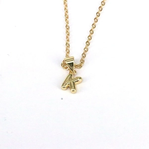 Minimalist gold necklace with a polished 26-letter K pendant on a pure white background