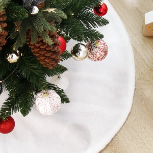 White faux fur Christmas tree skirt on wooden floor with festive holiday decorations