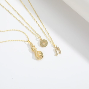 Detail of three gold necklaces featuring mermaid, compass, and zircon musical note pendants