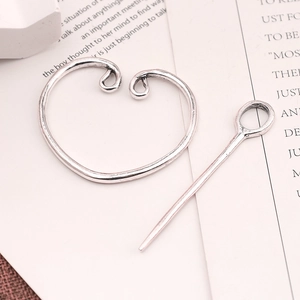 Detail shot of vintage silver viking brooch and shawl pin on aesthetic script paper