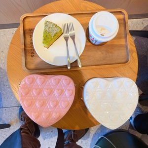 Chic heart-shaped crossbody bags in pink and white with quilted texture on a wooden table