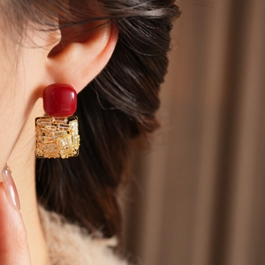 Close-up of model wearing square red and gold zircon earrings with a luxurious finish