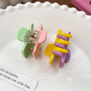 Candy colored macaron hair clips in a white ceramic plate for sweet styling