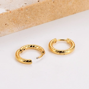 Golden stainless steel hoop earrings with textured spiral design on a stone base