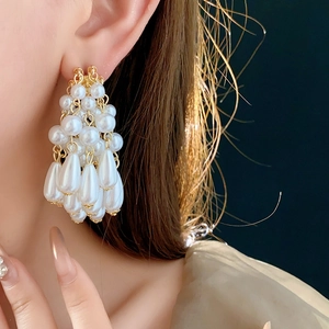 Detailed view of layered gold pearl tassel earrings worn on ear with drop shape detail