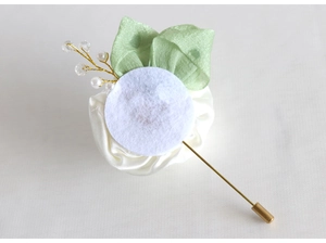 Detail view of handmade white satin rose brooch with gold needles and pearl accents