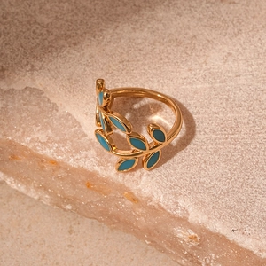 Detail of vintage gold leaf ring featuring green enamel inlay on natural stone background