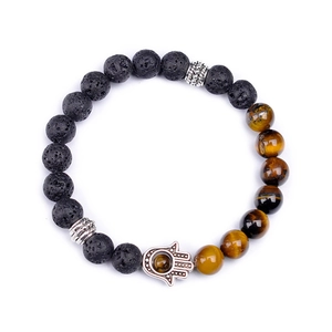 Handmade Hamsa hand bracelet with black lava stone and tiger eye beads on white backdrop