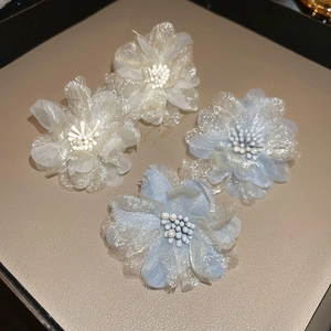 Detailed view of handmade mesh flower earrings in white and light blue with pearl centers