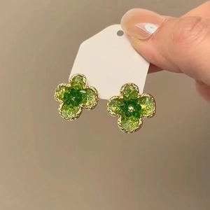 Detailed view of four-leaf clover stud earrings with green stone inlay and gold edges