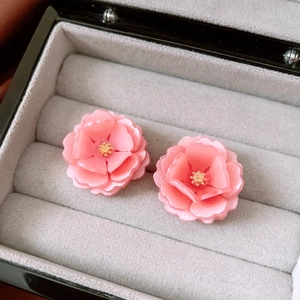 Detailed macro view of pink resin flower earrings with layered petals and gold centers
