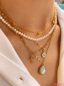 Detail of layered gold necklaces with heart, pearl, and cross charms on a model