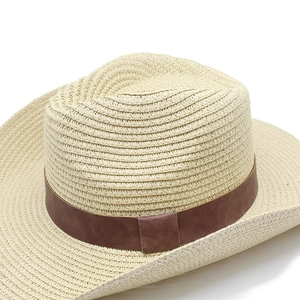 Detailed close-up of woven straw cowboy hat with brown leather band and fine texture