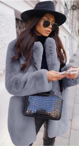 Gros plan d'un manteau en fausse fourrure grise avec sac à main noir et chapeau large