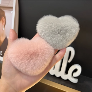 Close-up of pink and grey plush heart-shaped hair clips with soft faux fur texture