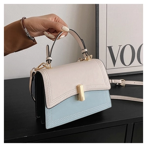 Détail d'un sac à main bicolore chic en beige et bleu avec un fermoir cylindrique doré