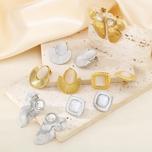 Detail shot of square cat-eye stone earrings and fan-shaped textured gold studs on stone