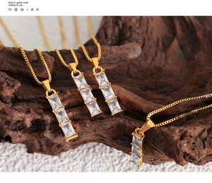 Close-up of gold titanium necklace featuring three tiered rectangular zircon pendants