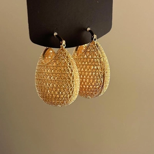 Detailed macro view of gold-colored hollow filigree teardrop earrings with vintage texture