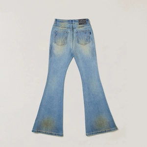 Macro detail of high-waist flared jeans featuring vintage wash and cross leather patch