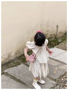 Top view of girl wearing a white textured dress with a pink pearl chain handbag