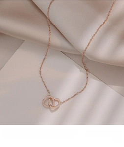 Close-up of interlocking heart pendants in rose gold finish on silk fabric background