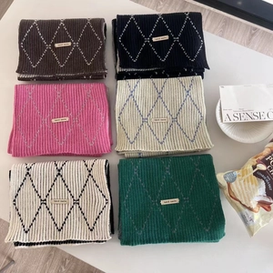Close-up of six colorful plaid knit scarves with handmade labels in a cozy layout