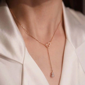 Rose gold titanium steel necklace featuring a pavé gourd pendant and heart charm on a model