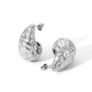 Macro shot of silver teardrop earrings with hammered metal texture on white background