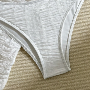 Detail of white textured ribbed fabric on bikini bottom with high-quality stitching