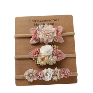Détail de trois bandeaux en nylon pour bébé avec fleurs artisanales et perles