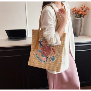 Straw shoulder bag featuring traditional dragon embroidery and decorative yellow tassels