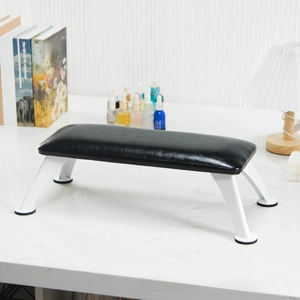 Close-up of black leather manicure arm rest with white metal legs on marble desk