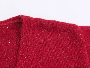 Gros plan sur le tissu d'un cardigan rouge avec fils argentés et petites paillettes