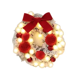 Christmas wreath with snowy pine branches, red bows, warm LED beads on white background