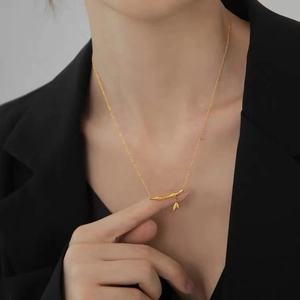 Close-up of minimalist gold bamboo pendant necklace worn with a stylish black blazer