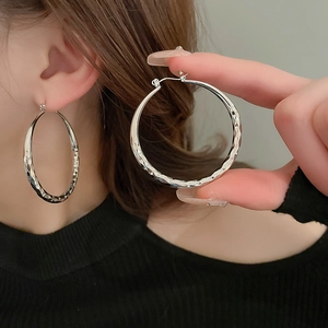 Detail of silver hoop earrings with diamond-cut texture shown on model for size comparison