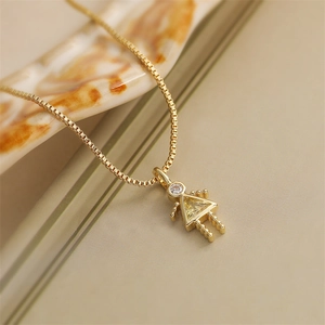 Macro detail of a golden necklace with a girl-shaped pendant and yellow crystal stone