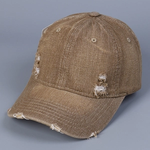 Detail view of distressed brown washed denim baseball cap with vintage frayed hole accents