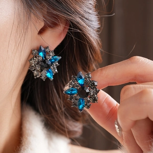 Dettaglio di orecchini a fiore vintage con pietra nera e gemme blu marquise